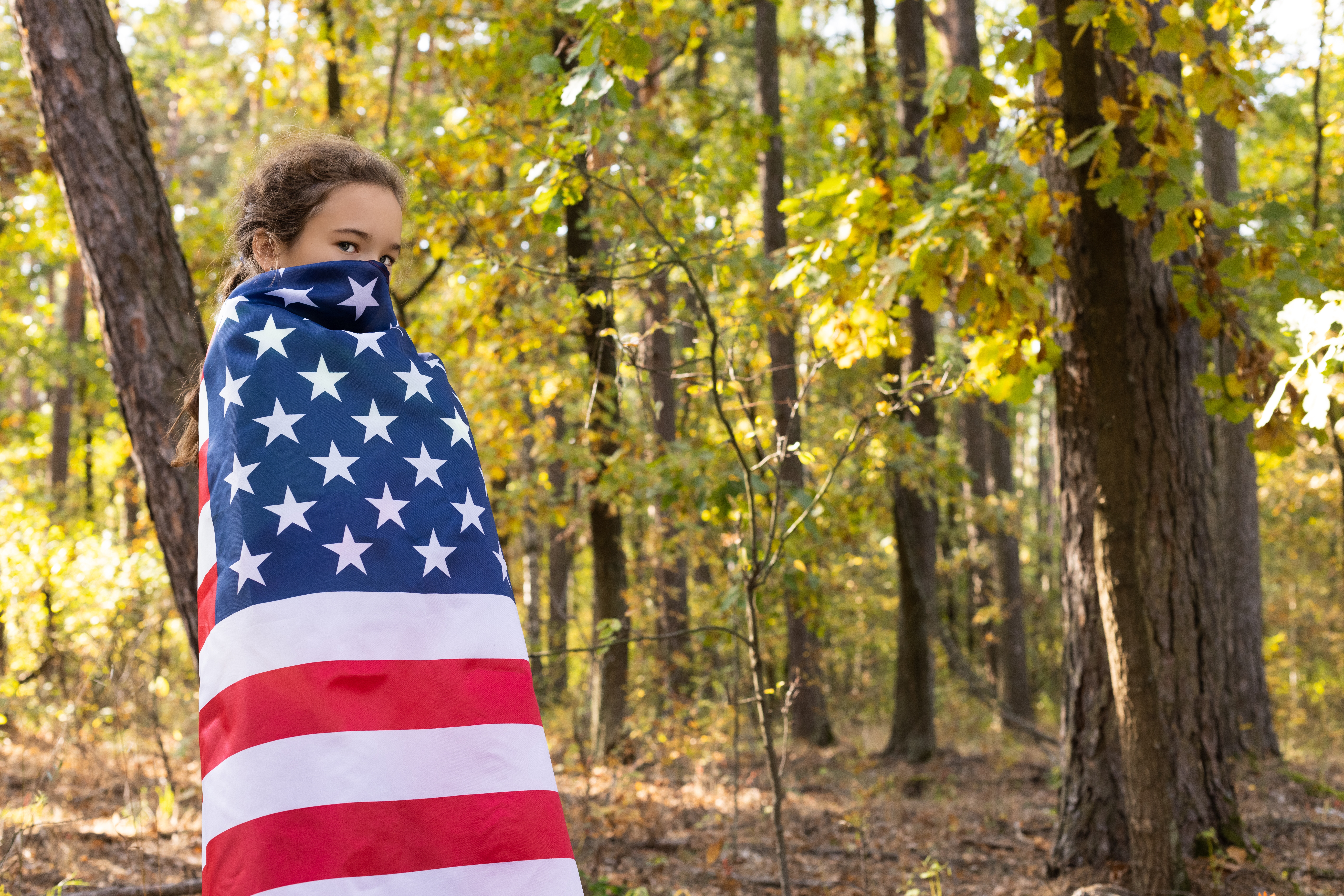 Little,Serious,Girl,Hides,Her,Face,With,Big,American,Flag.